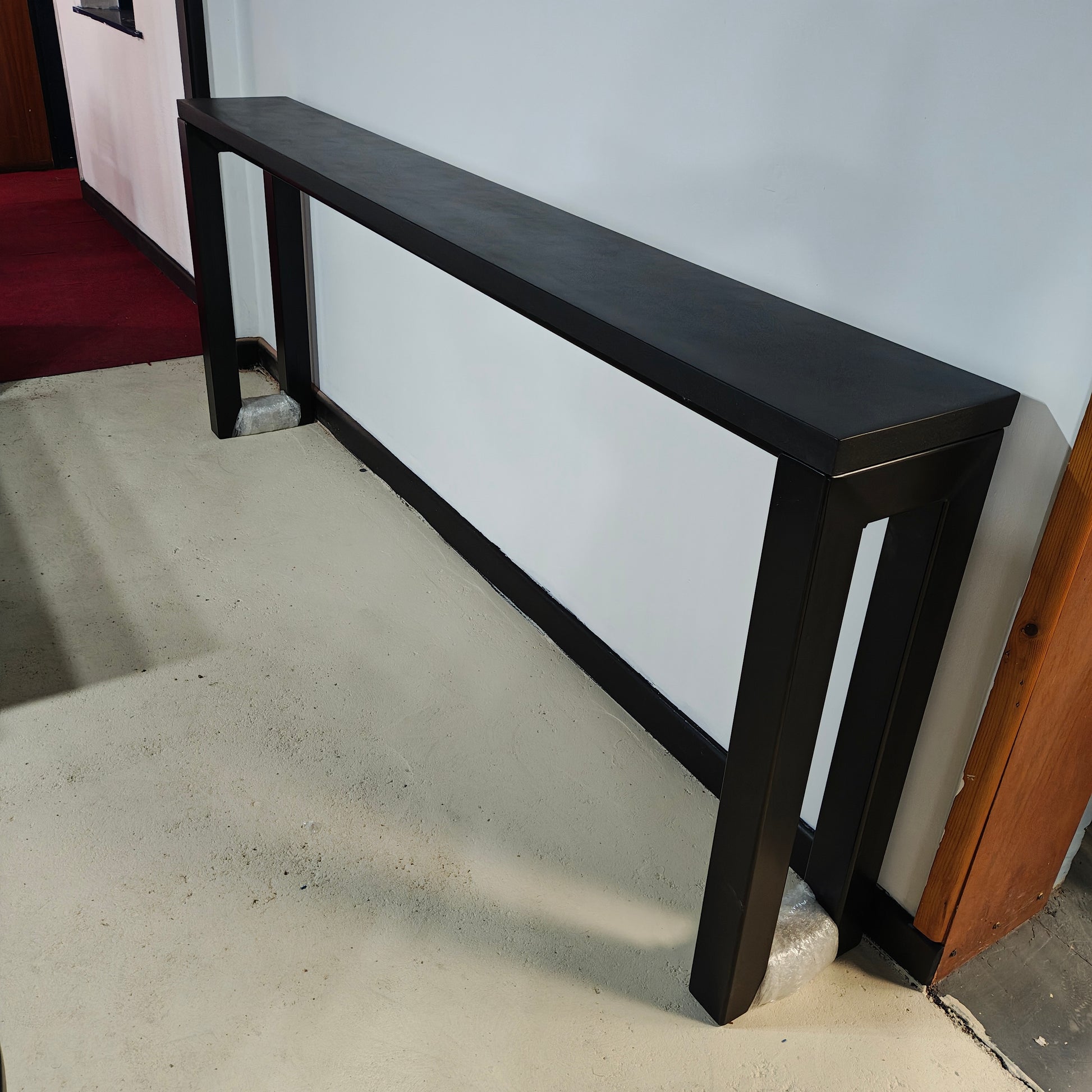 RockVine Artisan Surfaces Black polished concrete console table in a room with white walls and tiled floor